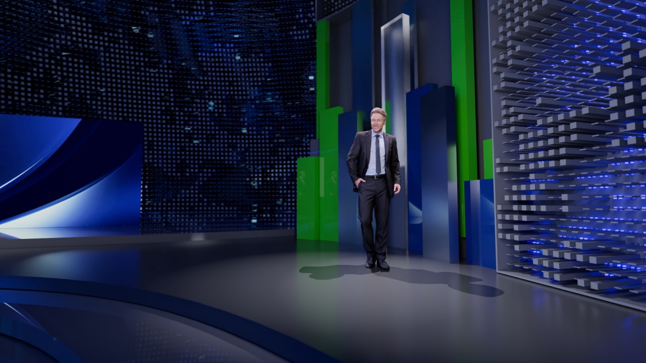 Presenter standing in an open studio zone with tall green-blue scenic elements and digital wall texture.