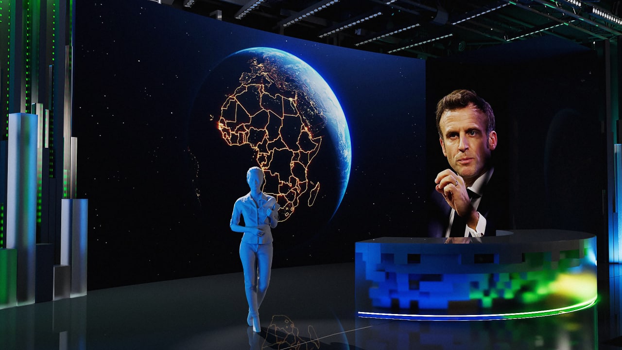 Curved desk studio with a globe-style wall visual and presenter interaction in a dark immersive set.