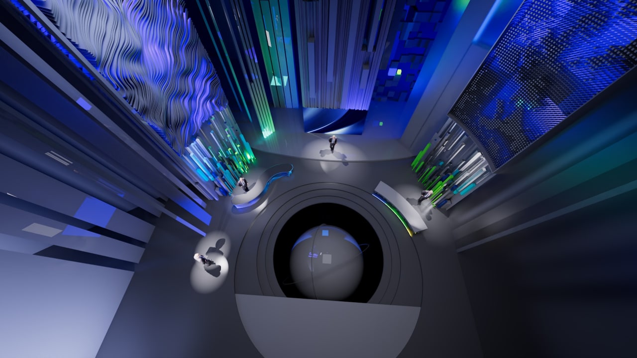 Overhead view of an immersive blue-green studio atrium with curved desks, layered ceiling elements and central circular focal point.